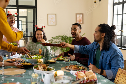 Christmas time, young multiracial friends enjoying festive holiday meal together, at home