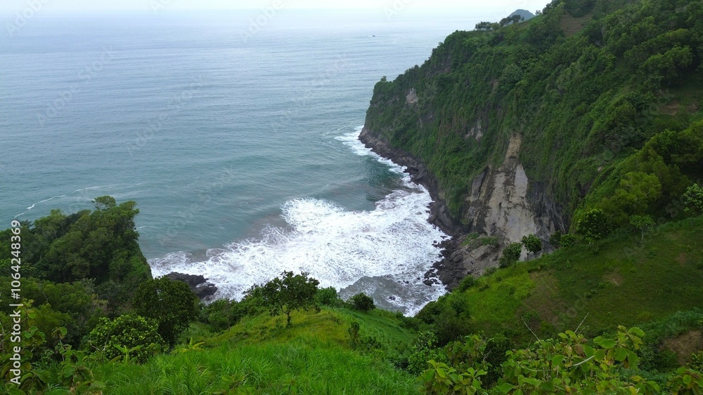 Drone view of Jerit hill Kebumen Indonesia, the seaside with beautiful hills and green trees, coral rocks, waves and ocean Drone view of Jerit hill Kebumen Indonesia, the seaside with beautiful hills and green trees, coral rocks, waves and ocean
