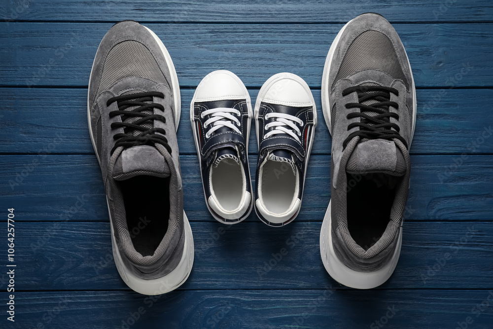 Big and small shoes on blue wooden table, top view