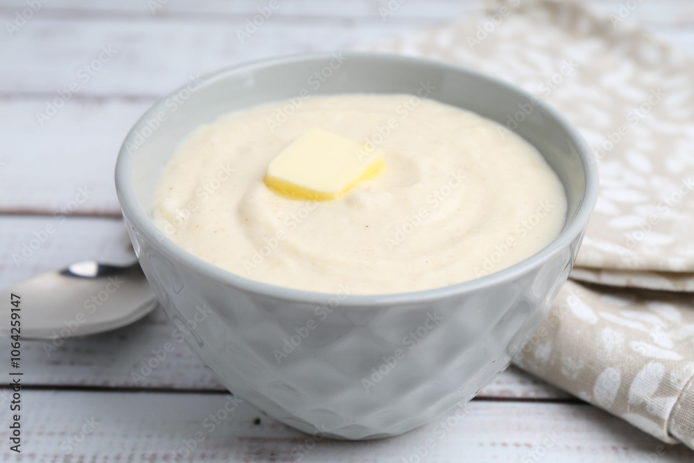 Tasty cooked semolina porridge with butter on white wooden table, closeup Tasty cooked semolina porridge with butter on white wooden table, closeup