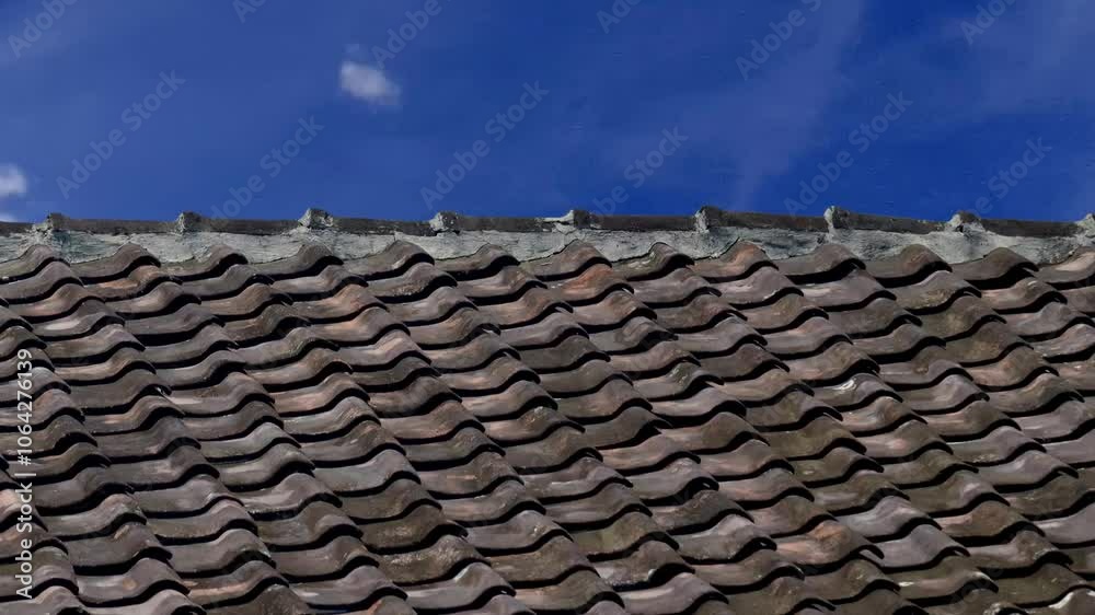 clay tile roof of an old house with moving sky and clouds in the background. clay tile roof of an old house with moving sky and clouds in the background.
