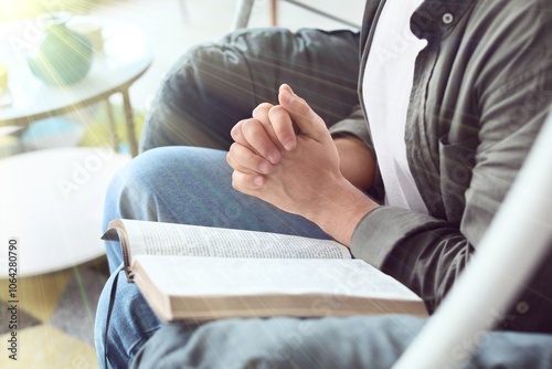 Young man with Bible prayin...