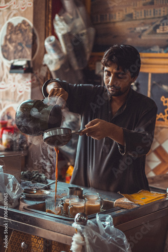 Fotografía Pakistani street vendor pouring chai tea into cups in his roadside tea stall