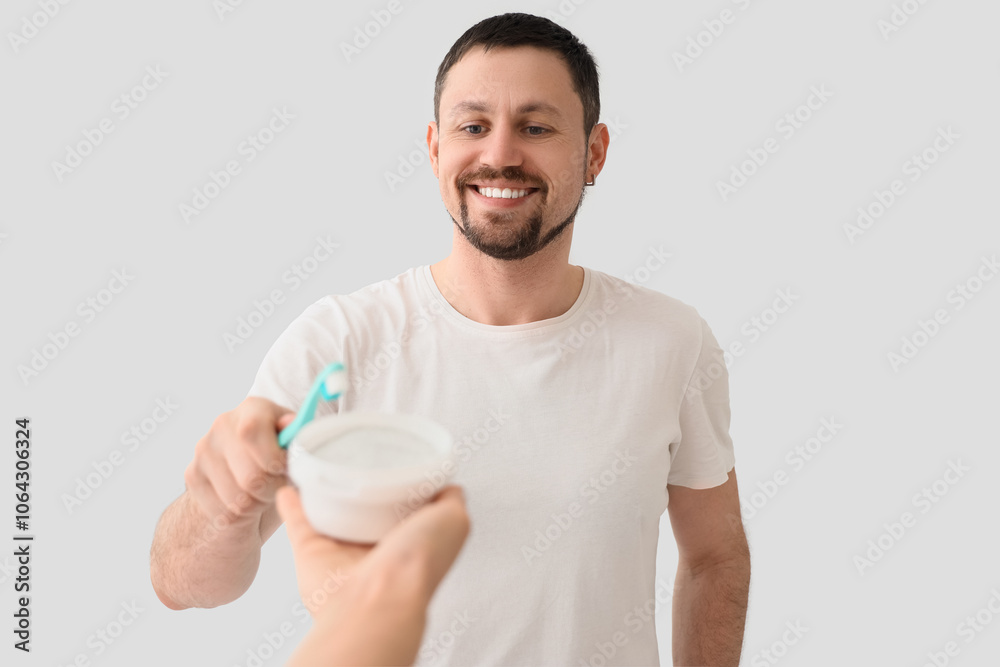 Young man with tooth powder and brush on light background Young man with tooth powder and brush on light background