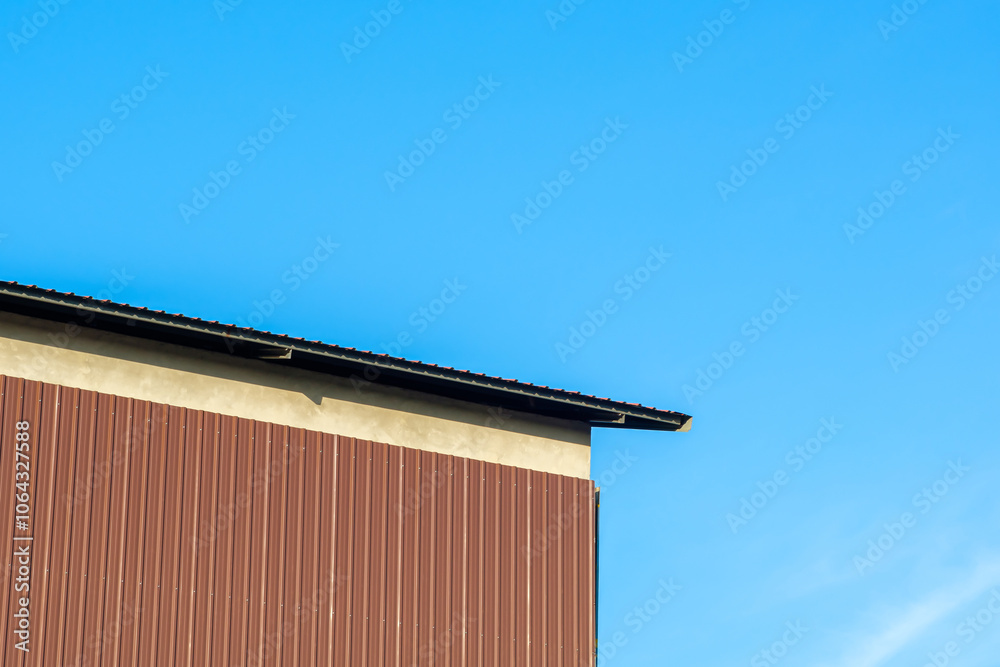 Brown metal sheet walls are attached to the concrete walls of a large factory. Brown metal sheet walls are attached to the concrete walls of a large factory.