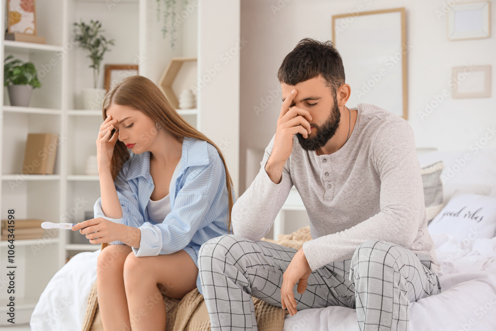 Upset young couple with pregnancy test sitting in bedroom Upset young couple with pregnancy test sitting in bedroom