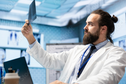 Licensed physician working on finding the right diagnostic with x ray scans results, examining bones radiography to detect illness. Medic analyzing healthcare records in hospital cabinet. photo