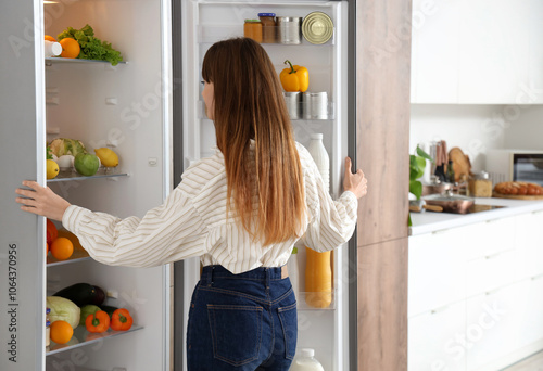 Young woman opening fridge ...