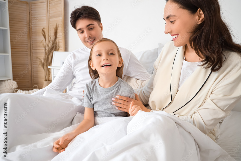 Little girl with her parents under blanket in bedroom Little girl with her parents under blanket in bedroom