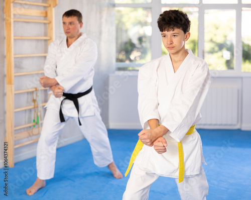 Active teenage male attendee of karate classes practicing kata in sports hall