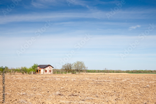 Rural house adjacent to expansive fields in Berkasovo, Serbia. with a panorama of fields, brown plowed field with furrows on Agricultural landscape, in countryside, berkasovo, Serbia, Voivodina. photo