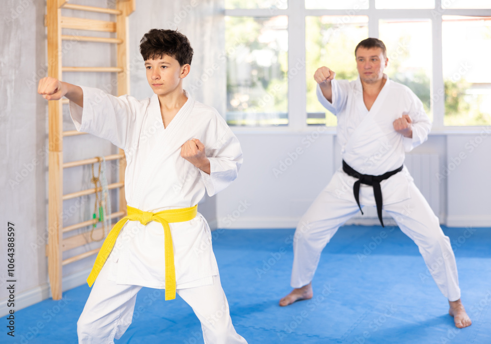 Obraz premium Karate trainer teaching block and punches to a teenager in the gym
