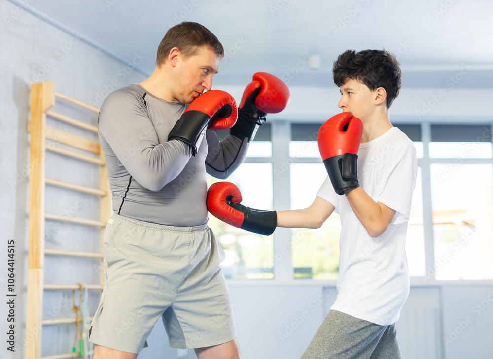 Father teaches son to box during individual boxing training in the gym Father teaches son to box during individual boxing training in the gym