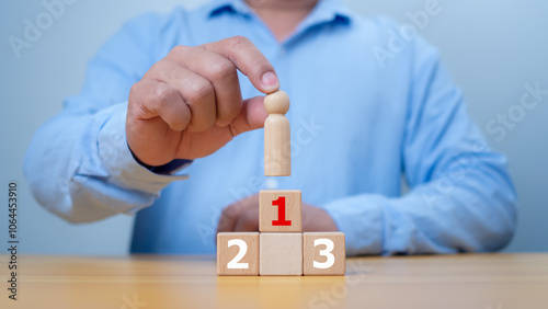 Hand man place wooden top of state or the winner. Concept of success, Winner and victory in business. A man holding wood person model standing on award podium, Leadership and superiority. photo