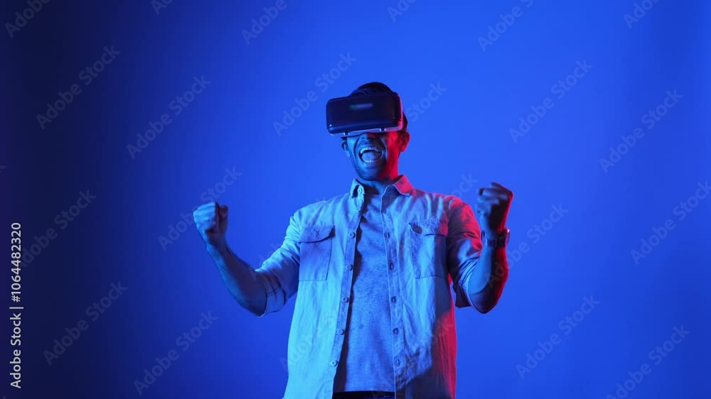 Attractive gamer with VR glasses and casual cloth celebrating for clearing game stage or winning the game. Smart businessman celebrate successful project or increasing sales. Technology. Apparatus. Attractive gamer with VR glasses and casual cloth celebrating for clearing game stage or winning the game. Smart businessman celebrate successful project or increasing sales. Technology. Apparatus.