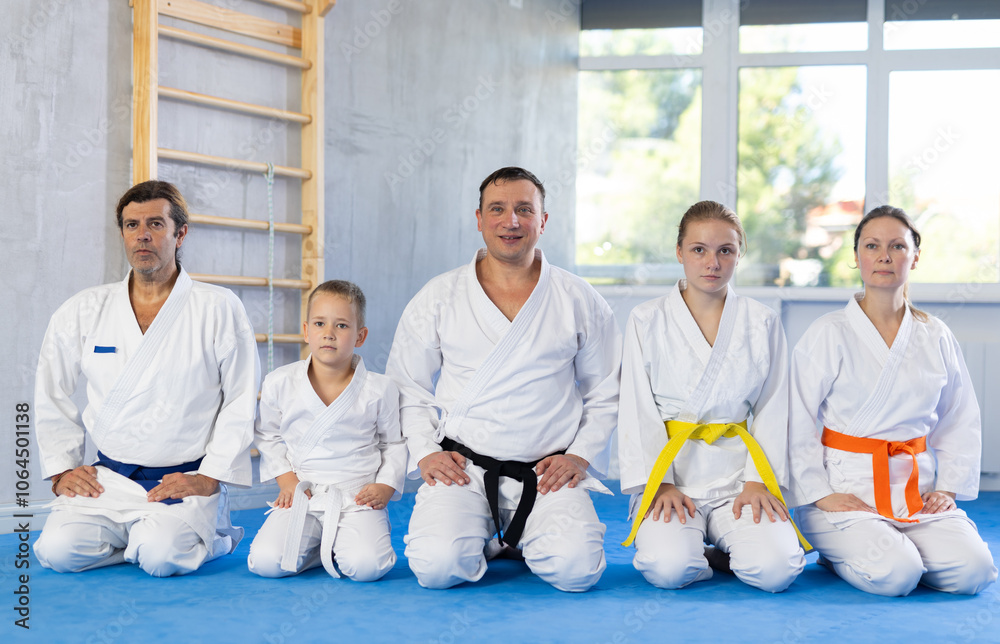 Family in gym at group karate training with trainer are in sitting position