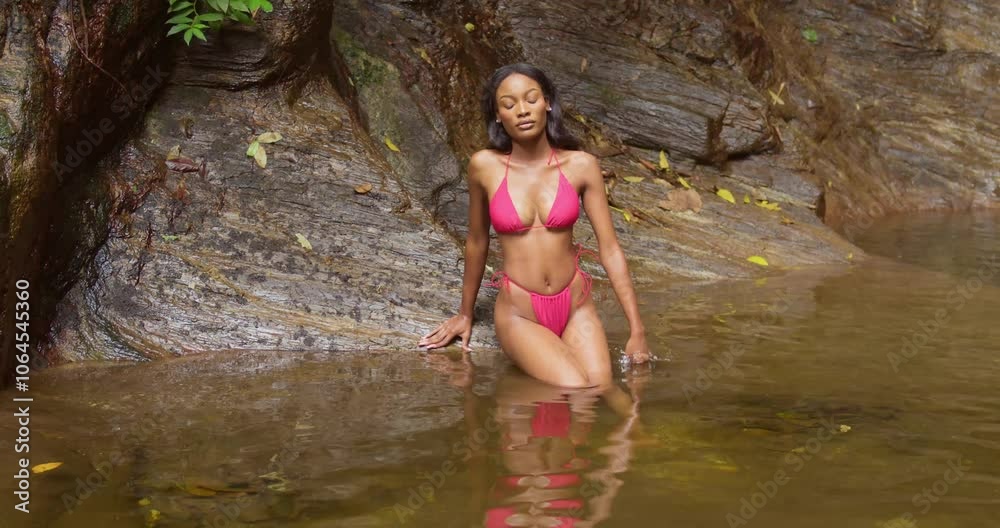 A girl in a bikini enjoys the natural beauty of a waterfall on Trinidad’s scenic island. A girl in a bikini enjoys the natural beauty of a waterfall on Trinidad’s scenic island.