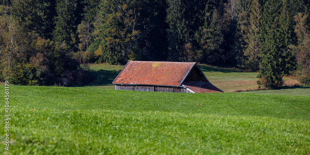 Fototapeta premium Scenic landscape of rolling hills of lush green fields and barn in Germany .