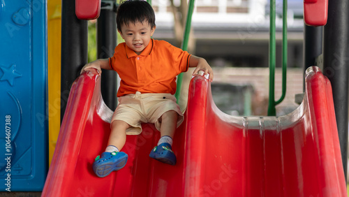 Happy young Asian boy enjoys playing at outdoor park #1064607388