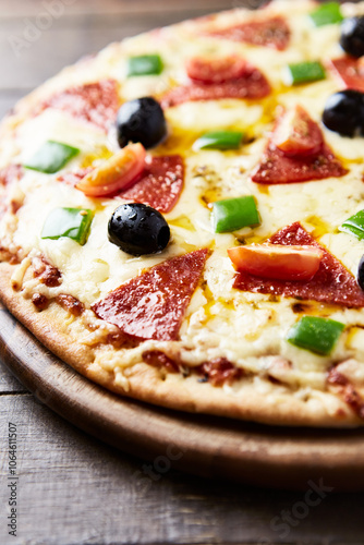 Pizza with salami and black olives. Home made food. Concept for a tasty and hearty meal. Wooden background. Close up. 