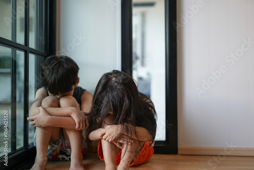 Sad siblings sitting with arms crossed in bedroom