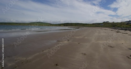 wide shot of port Logan beach looking north with dog running into frame at low tide photo