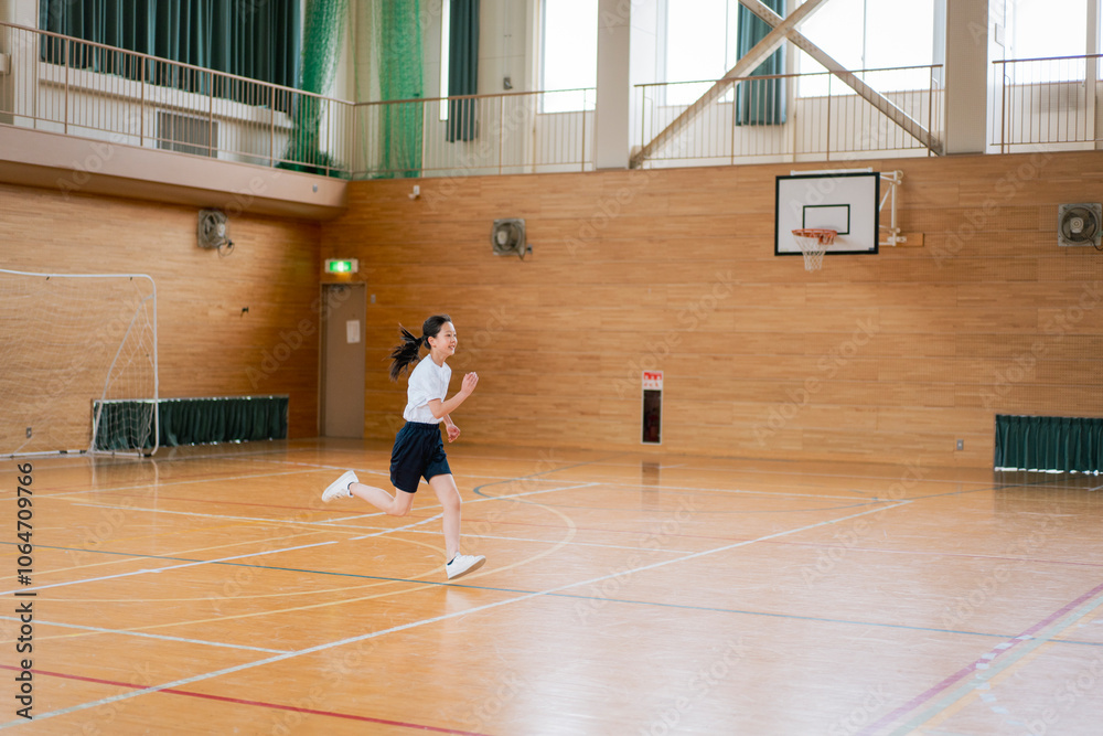 Obraz premium 学校の体育館の中で走る体操着姿の女子生徒