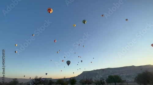 Hot air balloon atmosphere in Cappadocia, Türkiye, in blue clouds, surrounded by hills, captured using a handphone