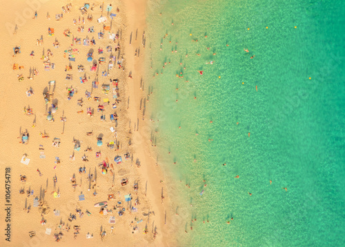 A top down scene of holidaymakers enjoying the beach and ocean.