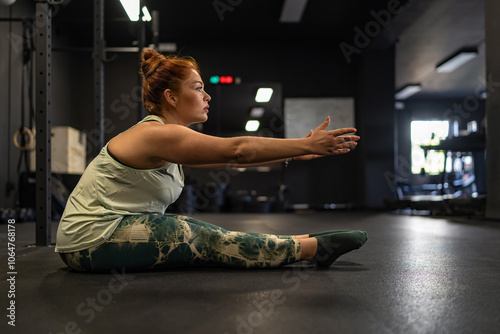 Determined woman practicing mobility exercise in modern gym space photo