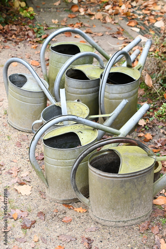 viele Gießkannen aus Blech stehen im Garten