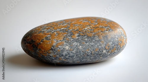 Closeup macro shot of a smooth,textured rock pebble with an organic pattern featuring shades of brown,orange,and gray hues.