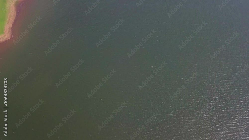 Serene aerial view of the calm waters of the Kabini River in Nagarahole, showcasing gentle ripples Serene aerial view of the calm waters of the Kabini River in Nagarahole, showcasing gentle ripples