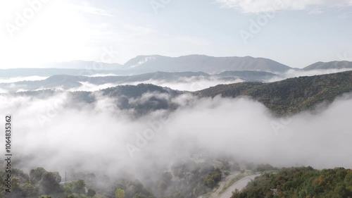 Wallpaper Mural Fog covering Mount Tymfi in a calm, moody aerial scene with mist rolling over rugged peaks, aerial trucking pan with town below Torontodigital.ca