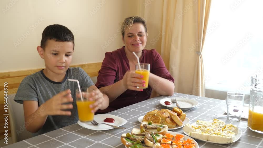 Mother and son drink juice while sitting at the table. Mother and son drink juice while sitting at the table.
