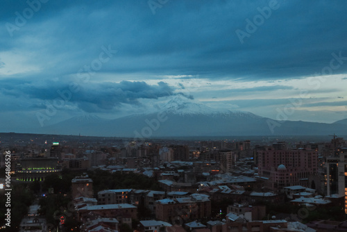 Views of Erevan under a dramatic sky with mountains in the background during twilight hours photo