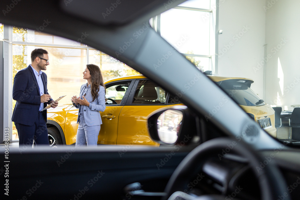 Super sales team in dealership, two consultants or managers in elegant suits with laptop and tablet in arms in car dealership Super sales team in dealership, two consultants or managers in elegant suits with laptop and tablet in arms in car dealership
