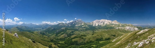 Vast panoramic view of rolling hills and majestic mountains in a clear blue sky during a sunny day in the countryside