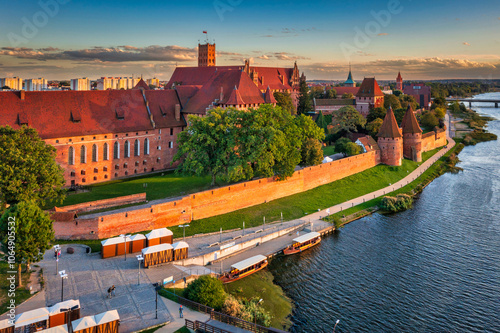 Castle of theTeutonic Order in Malbork by the Nogat river at sunset.