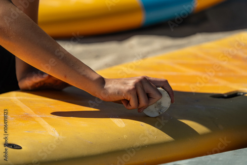 Surfboard wax. Hand holds a piece of surf wax and lubricates the surfboard. Waxing a surfboard. photo