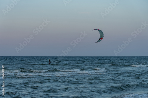 People swim on the sea on a kiteboard or kitesurfing. Kitesurfing lessons on the bay. Summer sport learning how to kitesurf. Kite surfing on bay. Hel Peninsula,Puck bay, Jastarnia, Poland.