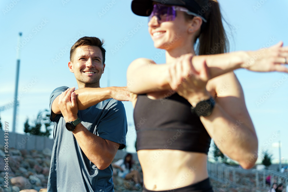 Fototapeta premium Outdoor Stretching Routine With Two Individuals Focusing on Fitness During a Sunny Day at a Recreational Park