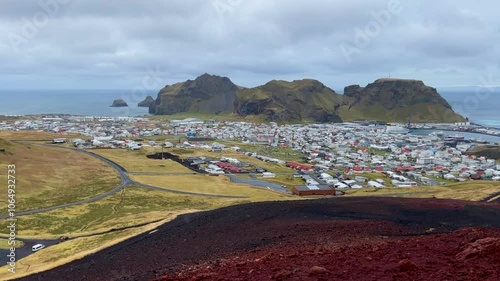 Red Rock Foreground Of Eldfell Volcano Near Vestmannaeyjabær Town At Heimaey, Iceland. Wide Shot photo