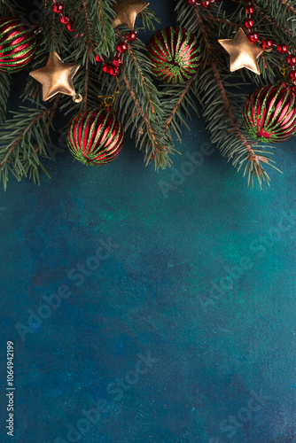 New Year and Christmas background. Fir branch with Christmas ornaments on a  dark blue-green painted wooden background.  Flat lay.