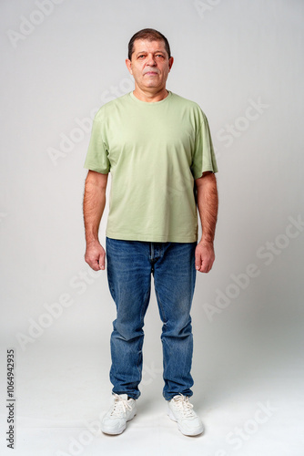 A man standing confidently in casual attire against a neutral background, showcasing a relaxed pose