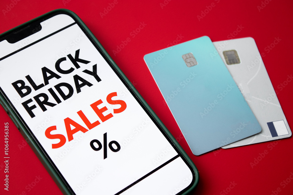 Close up of a smartphone screen displaying a Black Friday online sale on red background with credit cards and money Close up of a smartphone screen displaying a Black Friday online sale on red background with credit cards and money