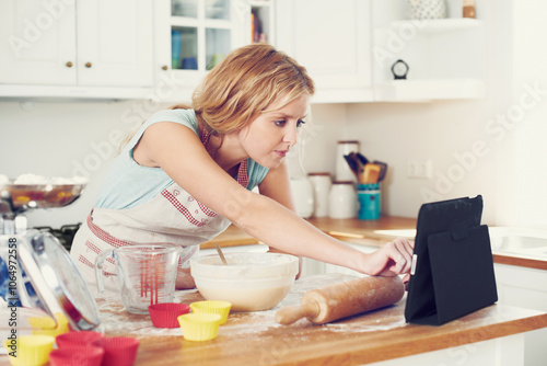 Woman, tablet and video in kitchen for baking, cookies and online with article, bowl and streaming. Female person, tech and recipe in home for cooking, cupcakes and food with flour, wheat and tips