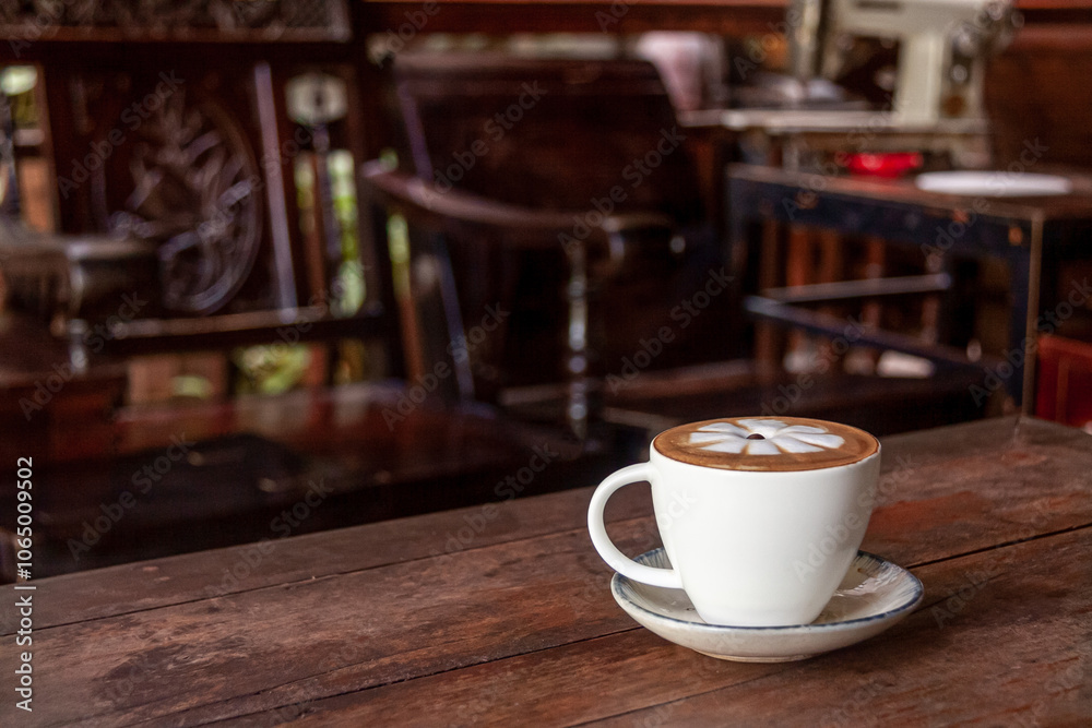 Fototapeta premium Cappuccino in a White Cup with some Wooden Furniture in the Background