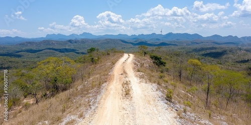 Aerial view of a dirt road winding through hilly terrain under a blue sky. photo