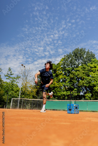 professional tennis court young curly guy technically performs the first serve in the game examines it clay court markings